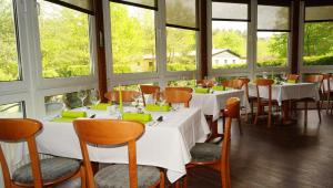 a restaurant with white tables and chairs and windows at Waldhotel in Boizenburg