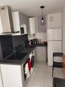 a kitchen with a black counter top and a white refrigerator at Home Up Bezons in Bezons