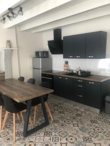 a kitchen with a wooden table and black cabinets at La Maison du Pêcheur in Portbail