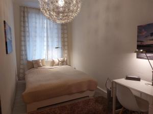 a white bedroom with a bed and a chandelier at Gemütliche Zwei-Zimmer-Ferienwohnung "W1" in Zwenkau bei Leipzig im Neuseenland in Zwenkau