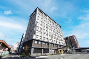 a tall white building on a city street at Onyado Nono Matsumoto Natural Hot Spring in Matsumoto