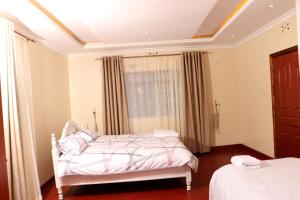 a bedroom with a white bed and a window at The Meru Manor in Meru