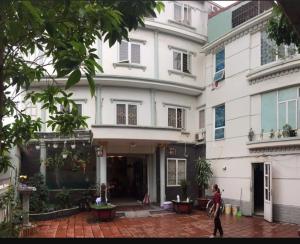 kobieta przechodząca przed białym budynkiem w obiekcie Motel TÂY HỒ w Hajfong