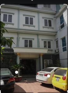 Biały budynek z samochodami zaparkowanymi przed nim w obiekcie Motel TÂY HỒ w Hajfong
