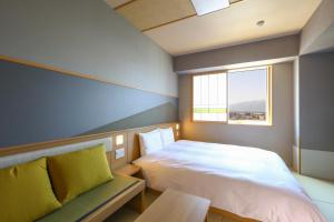 a bedroom with a bed and a bench and a window at Onyado Nono Matsumoto Natural Hot Spring in Matsumoto