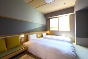 a bedroom with a white bed and a window at Onyado Nono Matsumoto Natural Hot Spring in Matsumoto