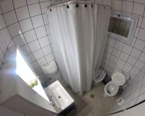 uma casa de banho branca com uma cortina de chuveiro e um WC. em 1 Habitación Alto Dorrego 5min de Mendoza Capital em Guaymallén