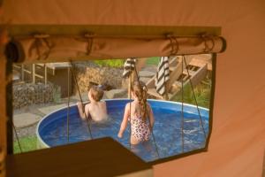 two children playing in a swimming pool at Sky Glamping boutique in Moshav Ramot