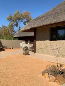 uma casa com um telhado de palha e um pátio em iKhaya LamaDube Game Lodge em Klipdrift