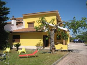una casa gialla con un albero e sedie di fronte di Villa Troianiello a Carano