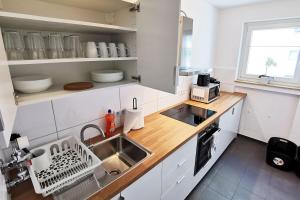 Biała kuchnia ze zlewem i blatem w obiekcie Nice apartment in Heusenstamm near Frankfurt w mieście Heusenstamm
