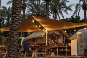 two people sitting at a table under a yellow umbrella at Sky Glamping boutique in Moshav Ramot