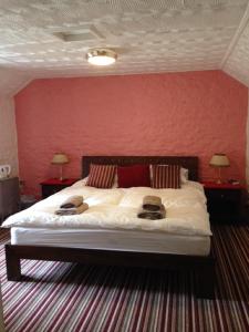 a bedroom with a large bed with a red wall at The Royal Oak Burford in Burford