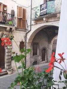 a building with an archway and flowers in front of it at Alloggi Piazza Umberto Primo in Pacentro