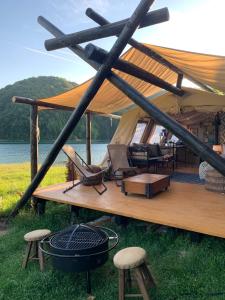 a gazebo with chairs and a grill on the grass at Luxury Lake House & Glamping in Teşila