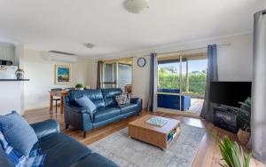 a living room with a blue couch and a tv at Carrawaves 73 LaRonde in Carrickalinga