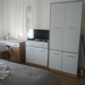 Kaptárkő Apartmanház في ديمجين: غرفة نوم مع مكتب وخزانة بيضاء كبيرة