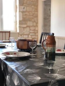 a table with a plate and wine glasses on it at Gîte de l'hortensia-Charmante maison de campagne au calme in Gourville