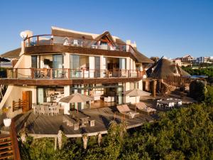 a large building with a deck with tables and umbrellas at Dolphin Sunrise in Jeffreys Bay