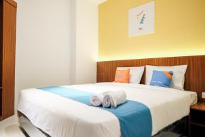 1 dormitorio con 1 cama grande y toallas. en Sans Hotel Roxy Jakarta en Yakarta