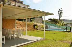 een patio met een tafel en stoelen en een tennisbaan bij Villa Valentina in Girona