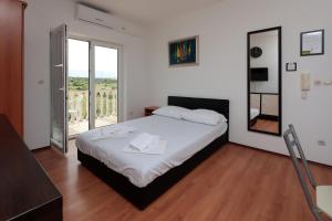 a bedroom with a bed with a mirror and a balcony at Apartments Peris Resort in Novalja