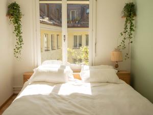 un letto bianco in una stanza con finestra di Stadtwohnung im Herzen von Bern mit Pool a Berna