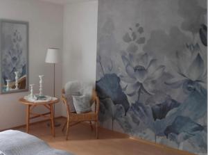 een kamer met een stoel en een muur met een muurschildering van bloemen bij 4 Sterne Ferienwohnung Rosengarten in Fürsteneck
