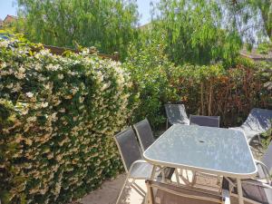 einen Tisch und Stühle in einem Garten mit Büschen in der Unterkunft tahiti parc maisonnette 6 pers 2 chambre in Le Lavandou