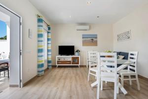 Una sala de estar con una mesa y sillas y un televisor. en Casa Orilla Sur A, en El Palmar