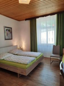 a bedroom with a bed and a chair and a window at Gästehaus zur Post - Heritage Inn in Spital am Pyhrn