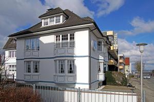 une maison blanche avec une clôture devant elle dans l'établissement Fischerhus Wohnung 4, à Cuxhaven
