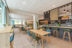 a restaurant with wooden tables and blue chairs at Holiday Inn Barcelona - Sant Cugat, an IHG Hotel in Sant Cugat del Vallès