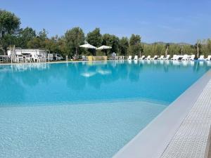 une grande piscine avec des chaises et de l'eau bleue dans l'établissement Resort Abbaia Ba, à Budoni