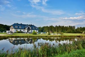 a house next to a lake with its reflection in the water at Dwór Nad Bugiem in Majdan Stulenski