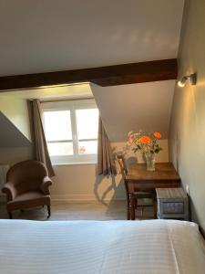 een slaapkamer met een bed, een tafel en een raam bij Hostellerie du Vieux Moulin in Autun