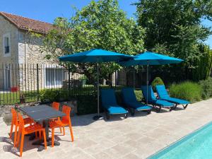 a group of chairs and tables with umbrellas next to a pool at Gîtes du Bonheur in Ausson