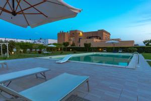 a swimming pool with an umbrella and two tables at Tenuta Giardini Nuovi in Novoli