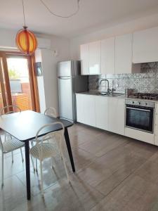 een keuken met een tafel, stoelen en een koelkast bij Kalura Sea House in Cefalù