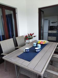 a wooden table with two cups and a bowl of fruit on it at Sweet Apartment With Private Pool Lori Ankaran in Ankaran