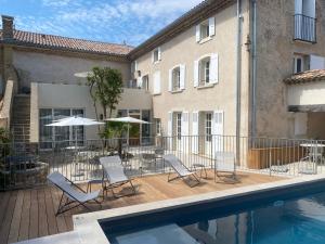 a pool with chairs and umbrellas next to a building at Villa Sainte Anne in Gigondas