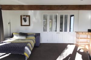 Schlafzimmer mit einem Bett und weißen Wänden in der Unterkunft Sunny Lakeside Haven in Queenstown