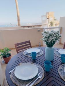 einem blauen Tisch mit Platten und einer Vase aus Blumen in der Unterkunft Apartamento con vistas al mar el Porís in Poris de Abona