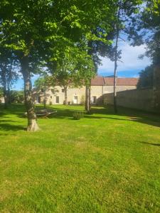 une cour verdoyante avec des arbres et un bâtiment dans l'établissement Les gîtes de ninon, à Moult