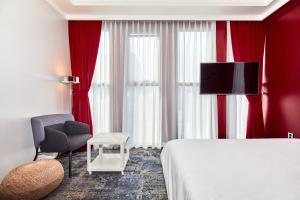 a hotel room with red curtains and a bed and a chair at Hotel POCO Seongsu in Seoul