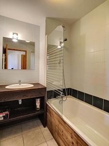 une salle de bain avec un lavabo, une baignoire et un miroir dans l'établissement Studio & piscine intérieure, vue Mont D'Arbois, à Saint-Gervais-les-Bains