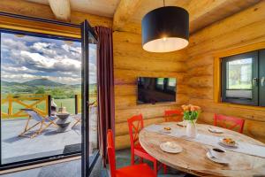 a dining room with a table and chairs and a large window at NOVAK CHALET domki z balią Krynica Zdrój in Krynica Zdrój