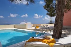 a swimming pool with a chair and a tree next to it at Aria Lito Mansion in Fira