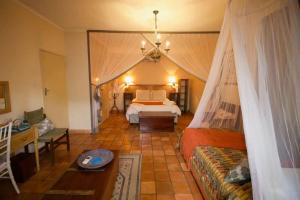 1 dormitorio con 1 cama con dosel en Wonderfully spacious two bedroom cottage in a quiet secluded area of town, on the edge of the bush - 1998, en Victoria Falls