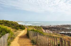 a dirt path leading to a beach with the ocean at Petite maison reposante pour 2 au bord de mer in Brétignolles-sur-Mer